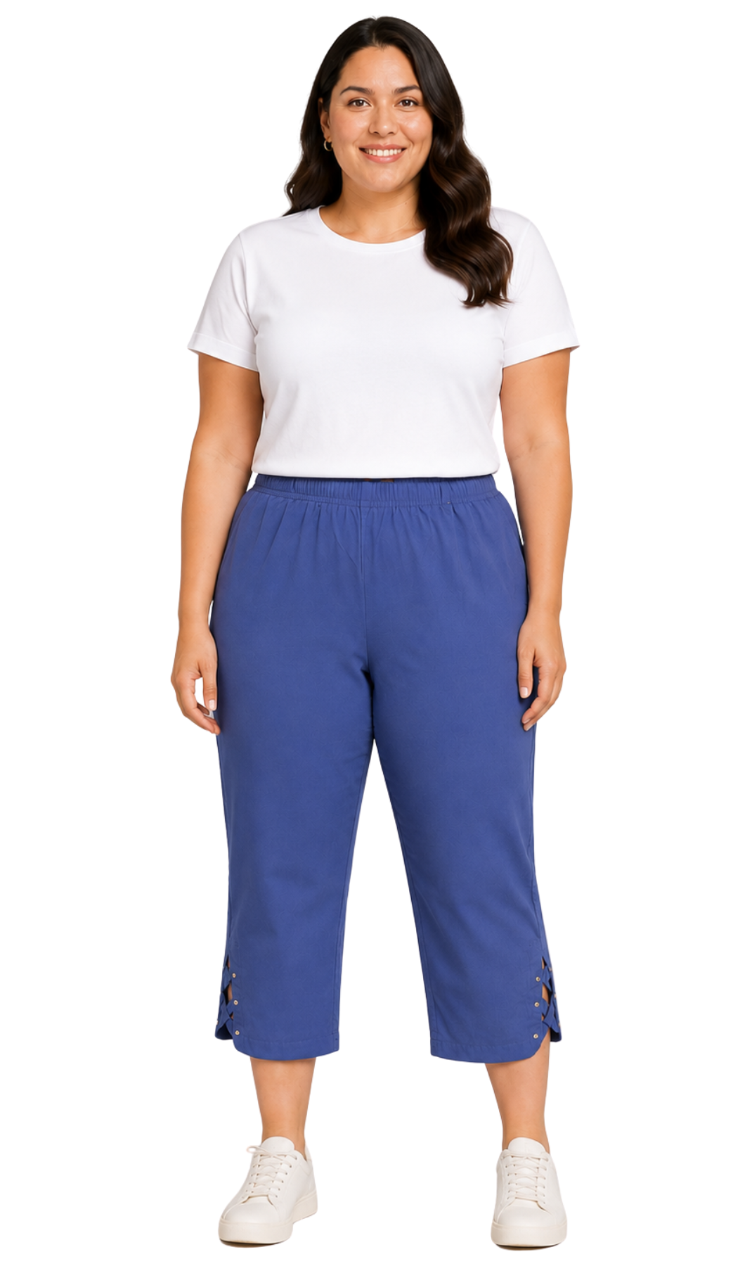 A woman modeling a pair of blue cropped pants with side buttons, paired with a white t-shirt and white sneakers, against a plain white background.