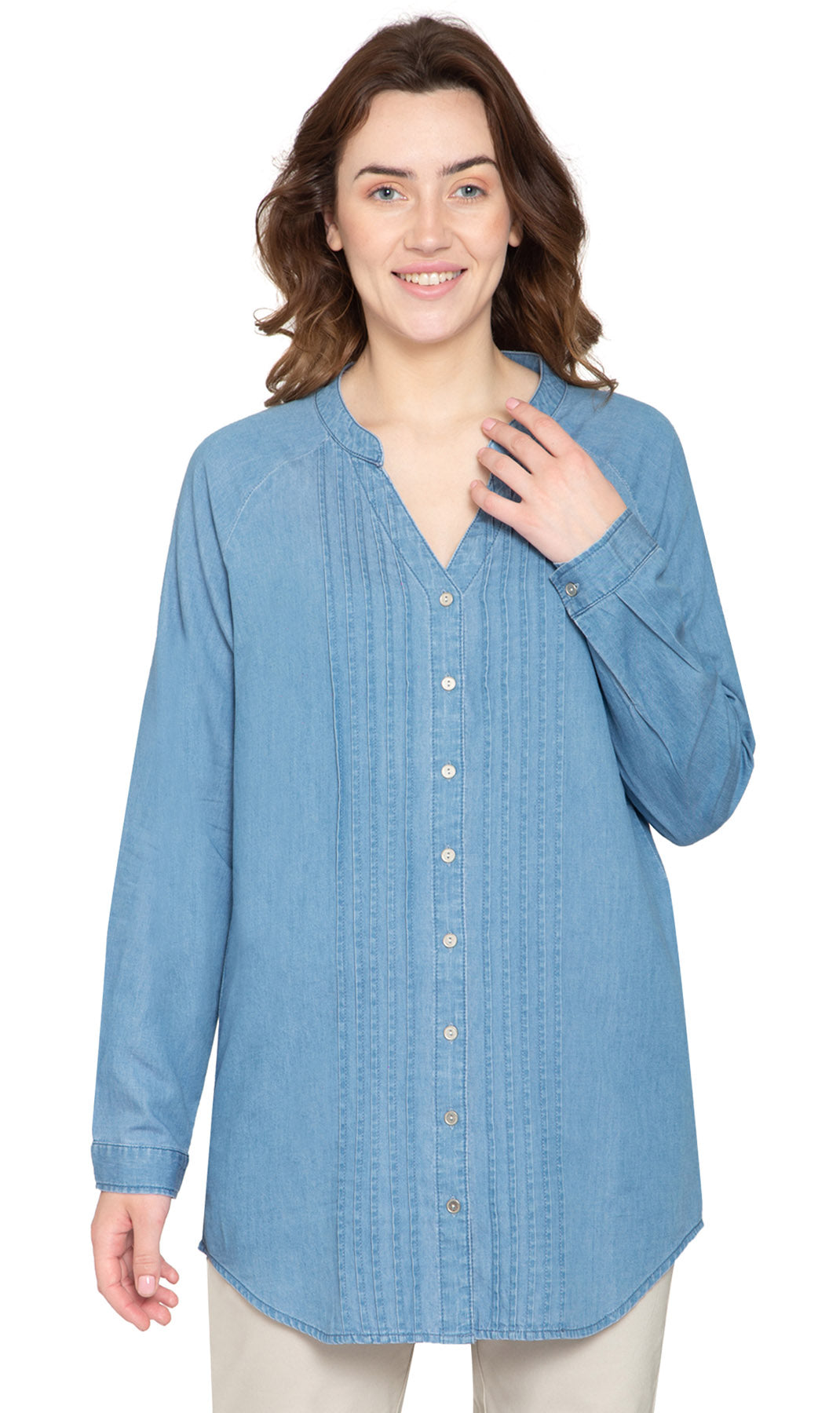 A woman wearing a blue denim tunic top with pintuck detailing and a button front, paired with jeans.